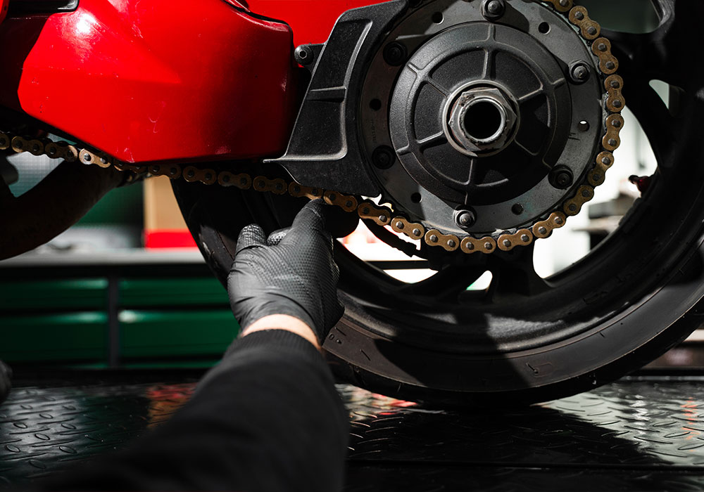 Arbeiten an Motorradkette und Hinterrad in der Werkstatt